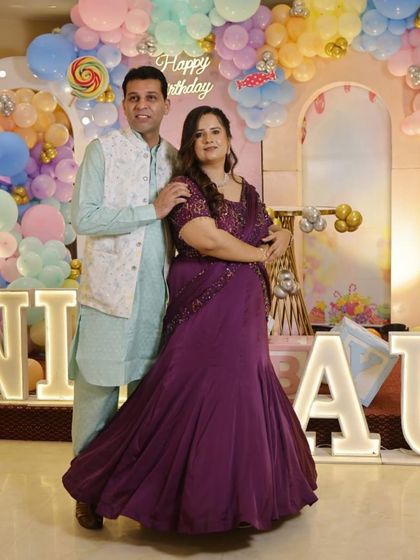This couple looks picture-perfect. Her purple drape saree gown was tailored to fit flawlessly, making it a comfortable yet elegant choice for a family function.