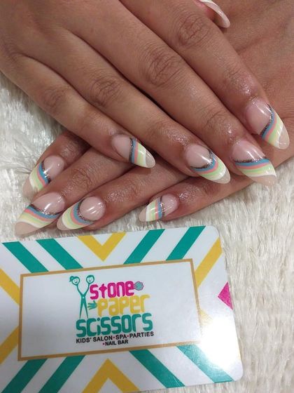 This design features delicate, curved rainbow stripes in pastel colors near the cuticle. It's a subtle and artistic way to add color to a natural-looking manicure.