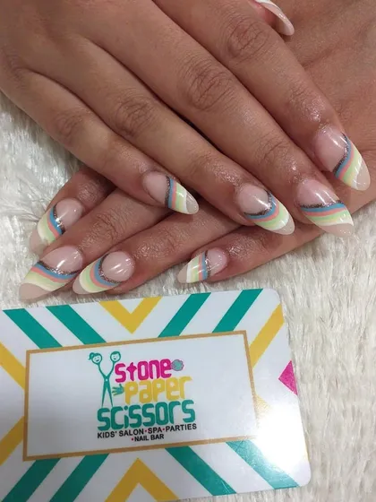 This design features delicate, curved rainbow stripes in pastel colors near the cuticle. It's a subtle and artistic way to add color to a natural-looking manicure.