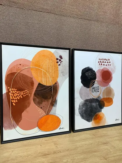 A side view of the framed abstract artworks, highlighting the clean profile of the veneer wood floater frames.