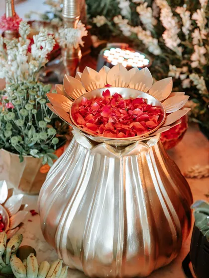 A beautiful brass lotus-shaped urn filled with fresh rose petals, a key element in our traditional Indian event decor.