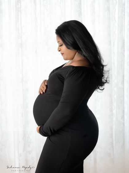 A side profile portrait in a timeless black dress. This pose is perfect for emphasizing the beautiful curve of the baby bump in a classic and sophisticated way.