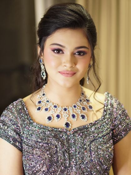 A portrait of regal elegance. The soft lilac shimmer on the eyes perfectly complements her stunning features and the deep blue of her jewelry, creating a harmonious and captivating look.