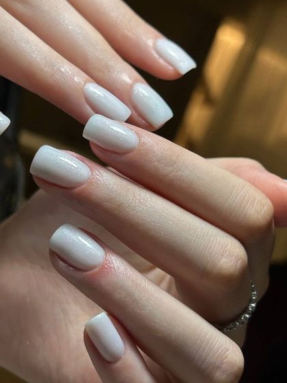 A soft and elegant milky white manicure on square-shaped nails. This look provides a more subtle, blended alternative to a classic French manicure.
