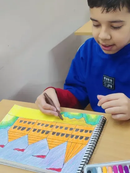 A student adding color to his drawing of a building. This exercise helps with understanding perspective and structure.