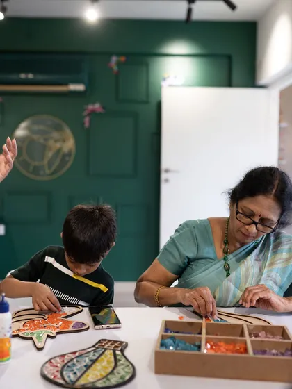 Art has a magical way of bridging generations. Here, a child and his grandmother work together on a mosaic piece, sharing a quiet moment of creativity and connection.