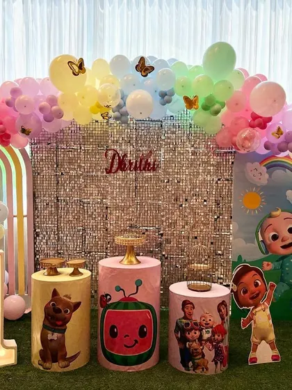 This Cocomelon first birthday party for Darithi is full of color and fun. We brought the popular show to life with character cutouts, a shimmering silver sequin backdrop, and a pastel rainbow balloon arch.