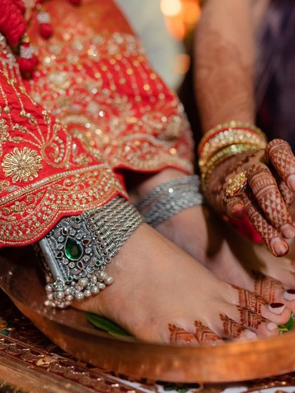 A detail shot of the bride's feet, adorned with stunning silver payals, during a wedding ritual.