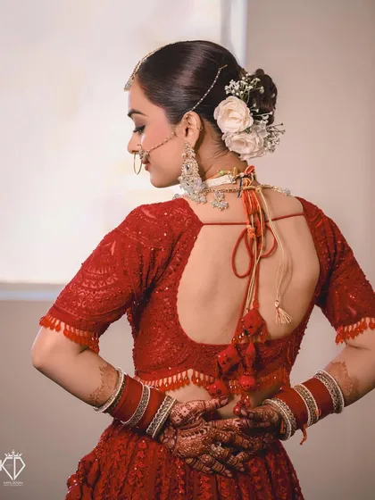 A detailed shot of the bride's back, showcasing the elegant blouse design and the floral arrangement in her hair. It’s a portrait that highlights craftsmanship.