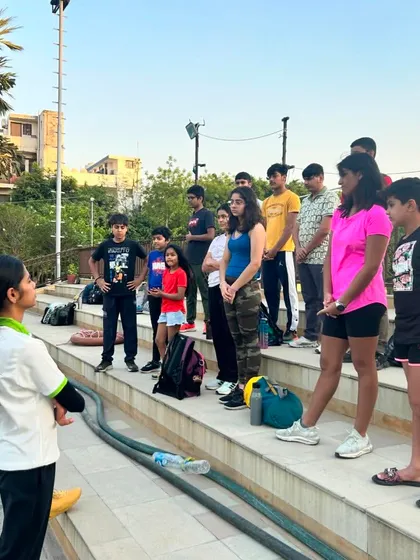 A group of our youth athletes listening intently during an outdoor briefing. We cultivate focus and discipline in all aspects of training, whether in the water, in the gym, or during educational sessions.