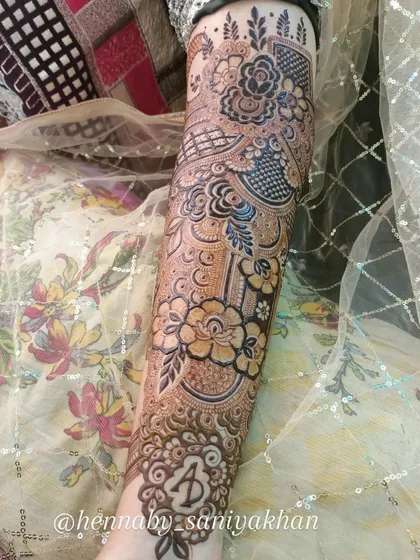 A close-up of the arm, showing the initial 'A' and the intricate floral work.