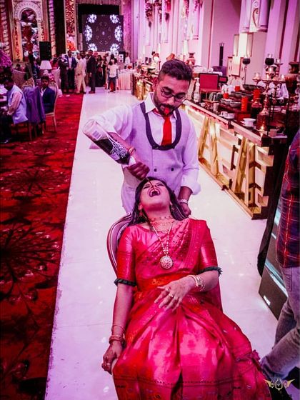 We're all about creating fun memories. A bartender playfully pours a drink for a guest seated in a chair, making for a great photo and a lot of laughs.