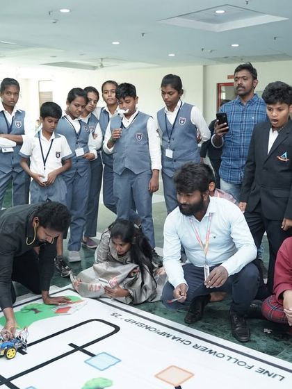 A team of students and mentors gather around the line-follower championship track. These events are a collaborative experience, fostering teamwork and peer-to-peer learning.