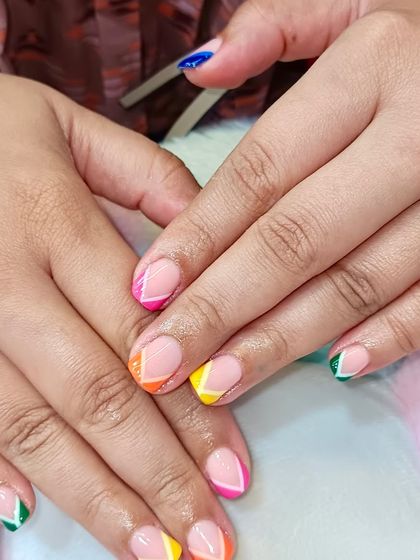 Proof that natural nails can steal the spotlight too. This playful look features a clean nude base with colorful, geometric French tips.