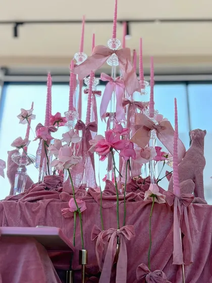 A close-up of the intricate centerpiece, with pink candles, ribbons, and flowers creating a tower of romantic elegance.