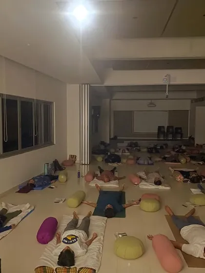 This is a moment of deep relaxation during a large group session. After guided movement and breathwork, participants rest in Savasana, allowing the body and mind to integrate the practice and find a state of complete stillness.