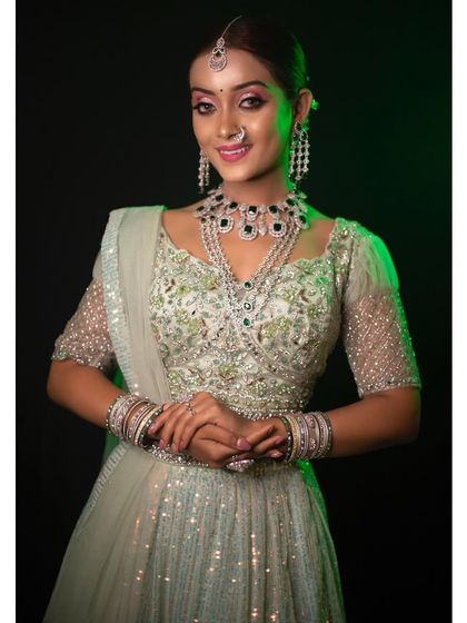 A beautiful portrait of a client wearing the pastel green sequin lehenga, paired with a stunning statement necklace set, also available for rent.