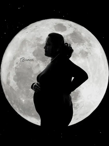 A beautiful silhouette of a mother-to-be against a full moon backdrop, creating a powerful and artistic image.