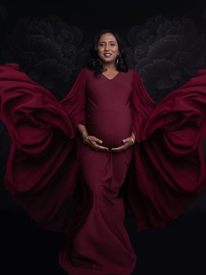 The flowing sleeves of this red gown create a beautiful sense of movement, like butterfly wings. This is a powerful and graceful maternity pose.