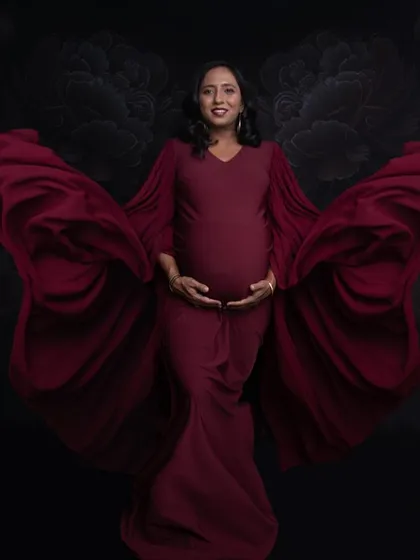The flowing sleeves of this red gown create a beautiful sense of movement, like butterfly wings. This is a powerful and graceful maternity pose.