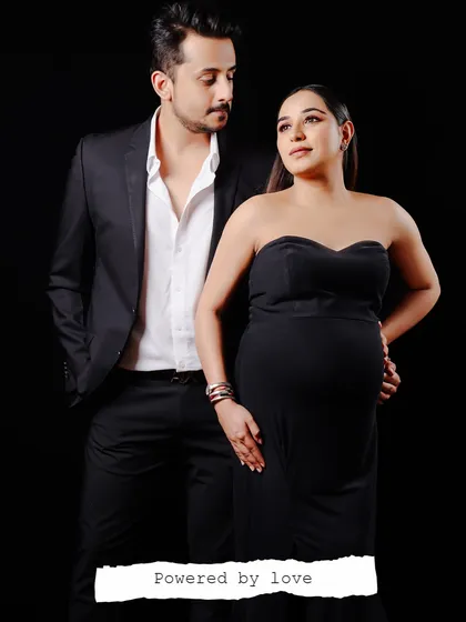 A full-length studio portrait of an expecting couple. The formal attire and their connected gaze create a powerful and elegant image that celebrates their partnership.