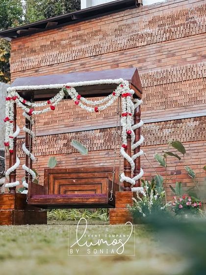 Another view of the traditional wooden swing, beautifully decorated and set against a brick wall.