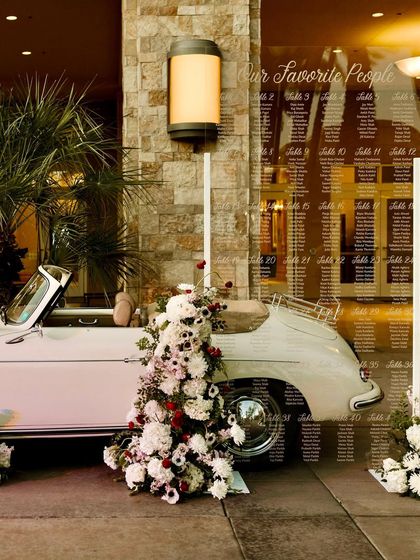 A creative seating chart display using a vintage car and a large acrylic sign. This is a fantastic example of how day-of stationery can be integrated into the overall event design.