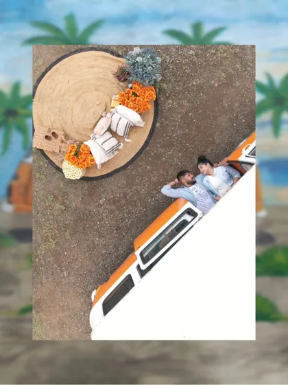 An artistic, top-down shot of the couple relaxing next to their van setup. This creative angle provides a unique perspective and highlights the beautiful, bohemian-styled picnic arrangement on the ground.