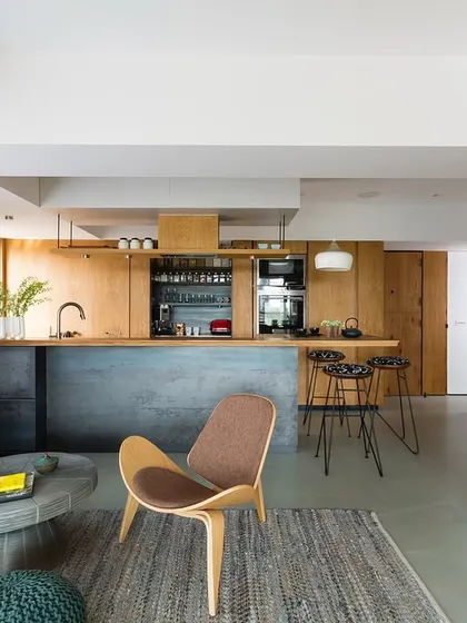 This is Casa Brio, our own home in Mumbai, presented alongside the Corner House to compare design approaches. It showcases an open-plan living and kitchen area with a focus on raw materials like concrete and wood.