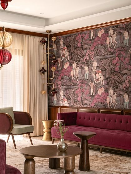 This living room is an exploration of maximalism, where a deep magenta velvet sofa is set against a rich, narrative wallpaper. We designed custom sculptural coffee tables and armchairs to create a layered, collected feel that is both bold and inviting.