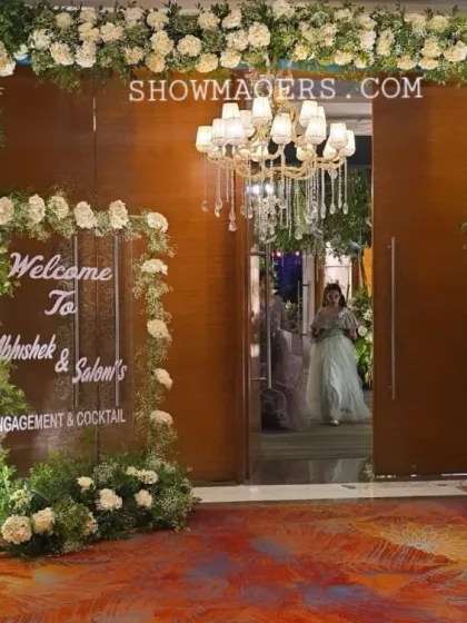 The entrance to Abhishek and Saloni's engagement, framed with lush white roses and greenery, leading into the main hall.