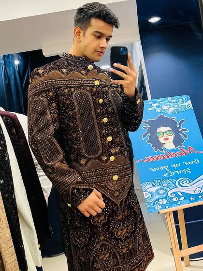 A customer's mirror selfie showing off the rich brown color and detailed pattern of this unique Indo-western sherwani.