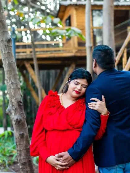 A tender embrace with a rustic treehouse in the background. This photo captures a cozy, intimate moment between the expecting couple.