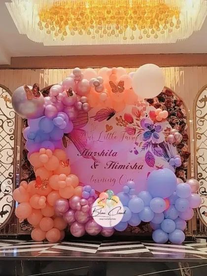 A beautiful custom backdrop for a twins' first birthday, framed by a pastel organic balloon garland.