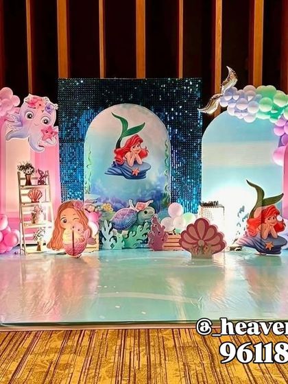 An elaborate stage setup for a Little Mermaid party, creating an under-the-sea kingdom. The design uses multiple backdrops, including a sequin panel, and pastel balloon arches to mimic ocean waves.