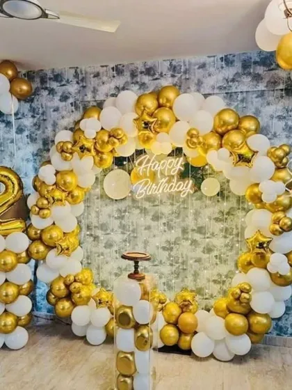A classic gold and white second birthday celebration. The circular balloon arch is paired with a number '2' balloon column, creating a timeless and elegant look.