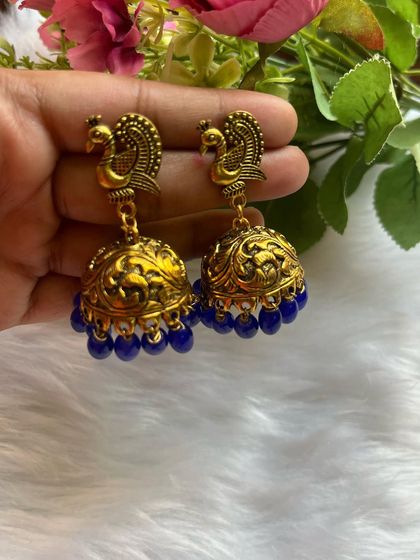 These gold-oxidised peacock jhumkas with royal blue beads are a regal and elegant choice for any traditional occasion.