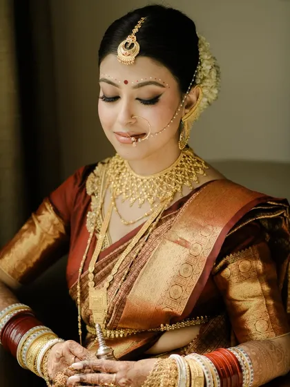 A moment of quiet contemplation before the ceremony. This classic portrait captures the bride's intricate makeup and jewelry, showcasing the timeless beauty of a Bengali bridal look.