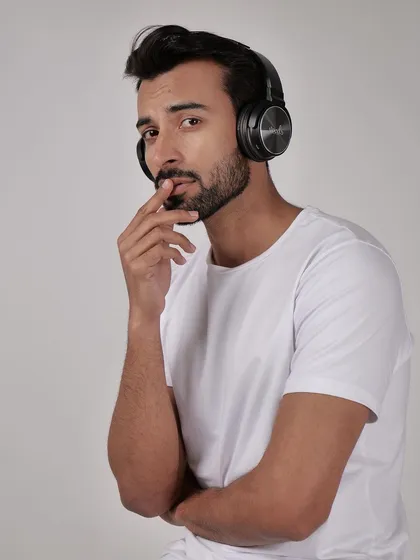 A lifestyle shot of a model wearing black headphones against a clean studio background. Using a model helps demonstrate the product's scale and how it looks when worn.