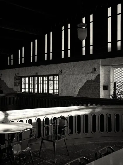 Another view of the dramatic shadows cast by the windows, creating a rhythmic pattern of light on the balcony railing.