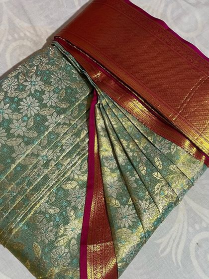 This light green floral saree with a red border is perfect for spring events. It's pleated and ready to wear.