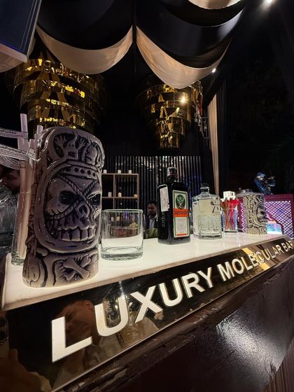 A close-up of our stylish bar counter, featuring our illuminated brand name and quirky, skull-themed tiki mugs.