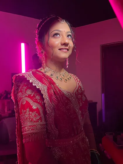The same bride, captured indoors with dramatic pink lighting, showing how the makeup adapts to different lighting conditions.