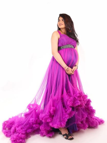 A full-length view of this dramatic purple ruffled maternity gown. The long trail adds a touch of glamour to any maternity photoshoot.