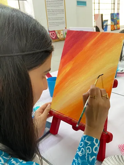 A participant paints a vibrant sunset on her canvas. The studio is always filled with color and creativity.