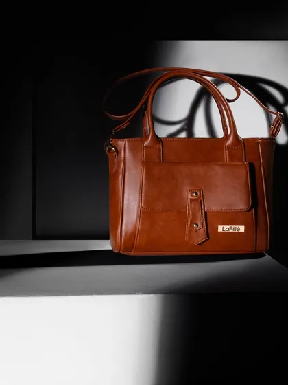 A dramatic shot of a brown handbag using strong shadows and highlights. This "chiaroscuro" lighting technique creates a moody, sophisticated atmosphere and makes the bag look like a piece of art.