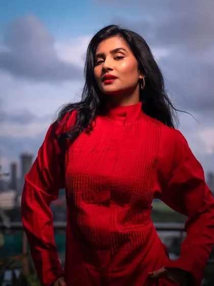 A close-up portrait in the red outfit, with the wind in my hair and the city behind me.