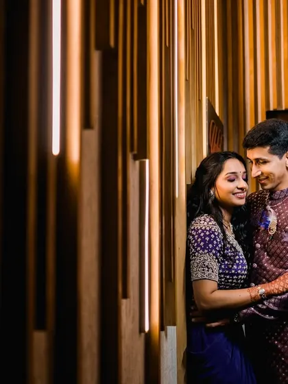 An intimate embrace against a warmly lit, textured wall. The side lighting creates a dramatic and romantic mood, highlighting their profiles and close connection.