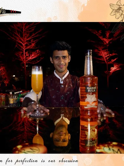 A bartender presents a vibrant orange cocktail, perfectly garnished and ready to be enjoyed.