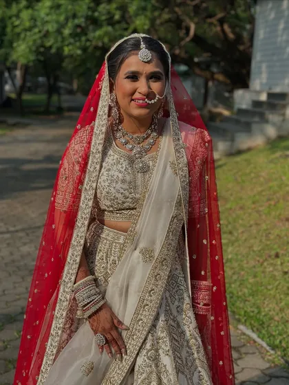 A beautiful portrait of the bride in her stunning ivory lehenga with a traditional red bandhani dupatta, a nod to her heritage.